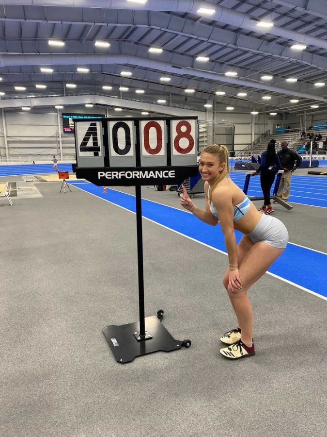 Senior Stephanie Robson posing next to her personal record sign at the Virginia Beach Sports Center.