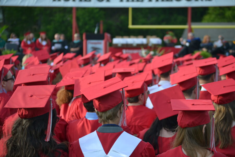 Previous Graduates wait on Falcon Field for their diplomas