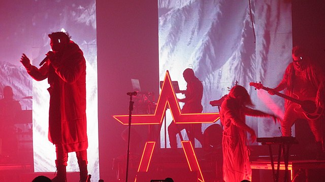 Starset performs under the hue of a red light.