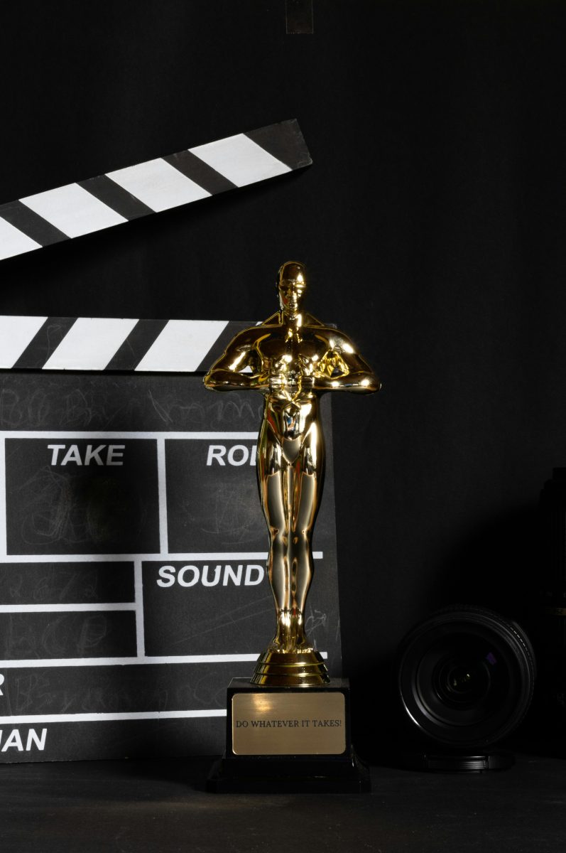 An+iconic+Oscar+award+with+a+clapper+board+in+the+background.