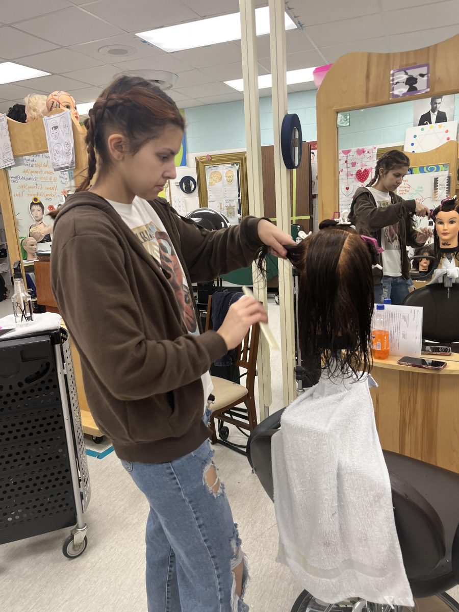 Junior Ashley Quiniones works on hair styling during cosmetology class.