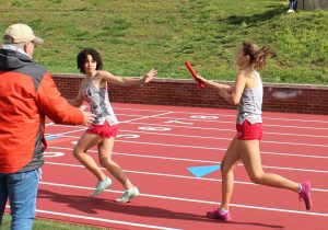 Kayana Frisk being passed a baton by another athlete during a relay race. 