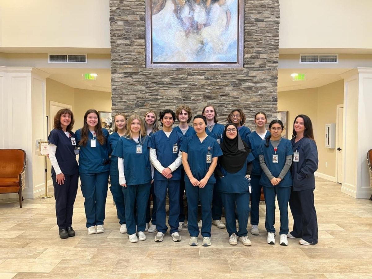 Nursing aid students stand proudly in White Springs Senior Living Facility, serving with care and pride.