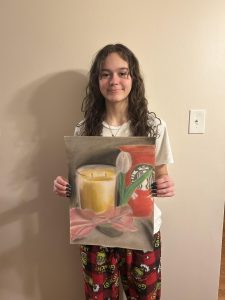 Caylee Hunt holding one of her skillfully-made paintings.