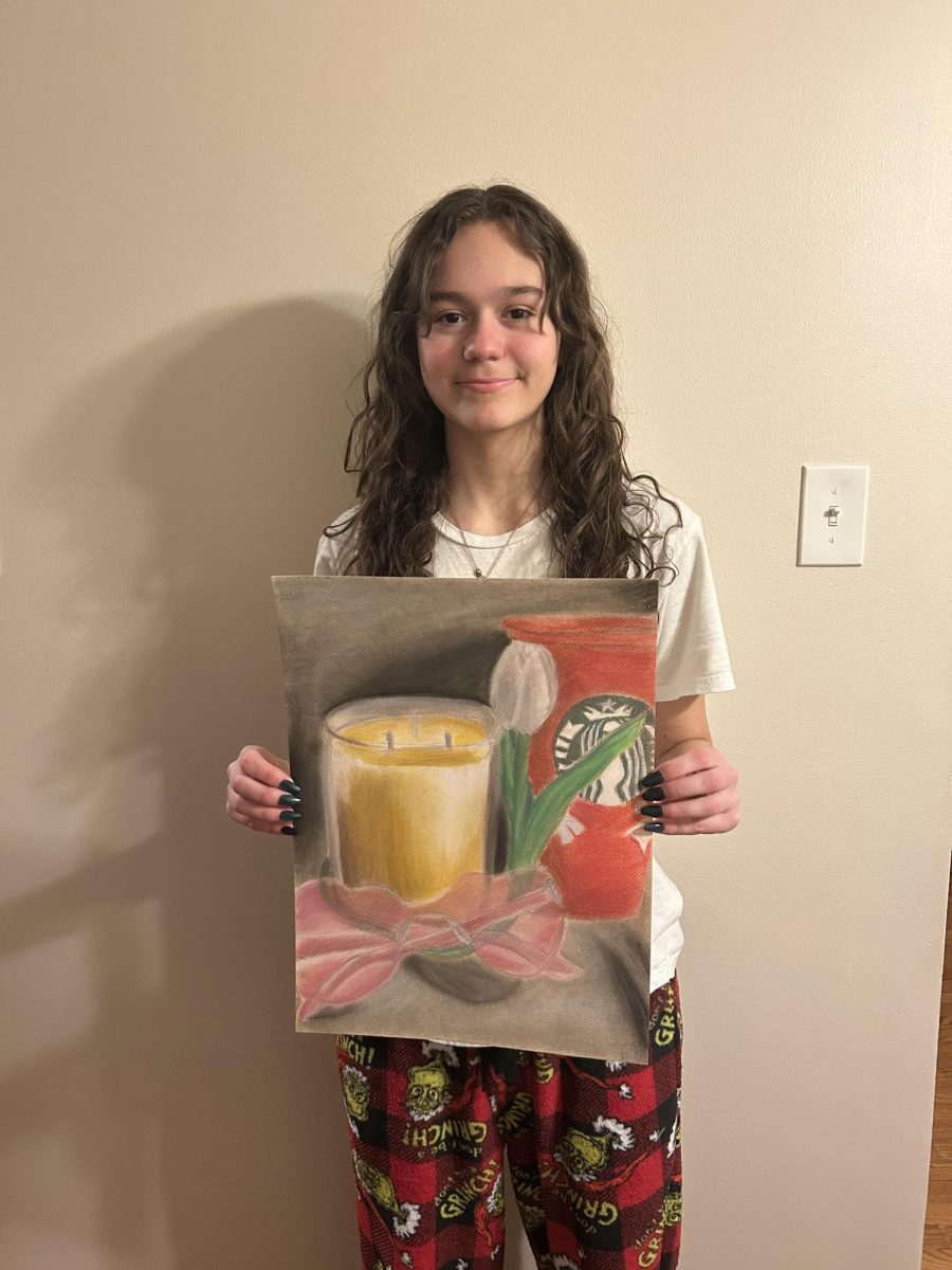 Caylee Hunt holding one of her skillfully-made paintings.