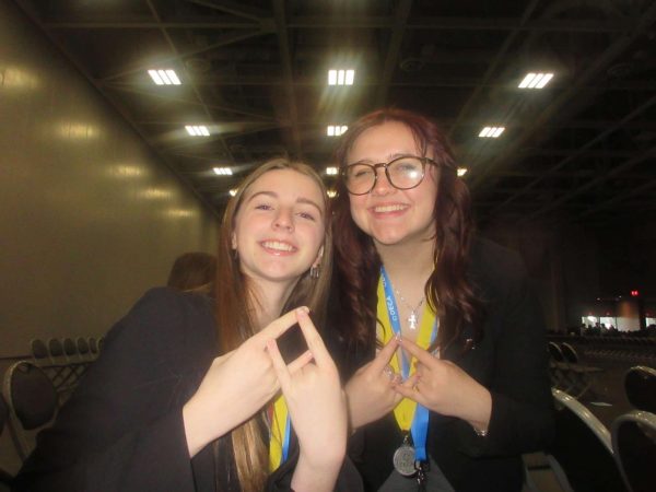 President and senior Izzy Breakiron (right) and Vice President of Finance and senior Meaghan Dysart-Moore (left) display the DECA symbol during the State Leadership Conference 