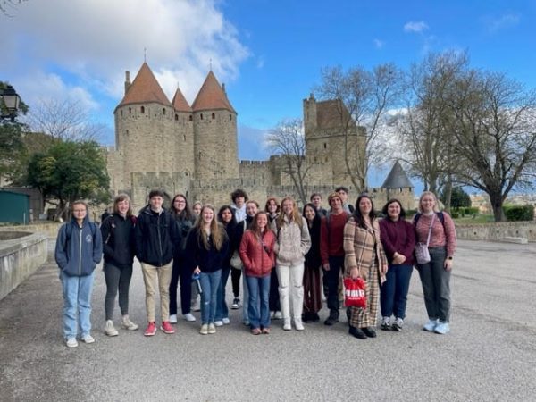 The French students posing for a picture in front of a medieval castle in France.