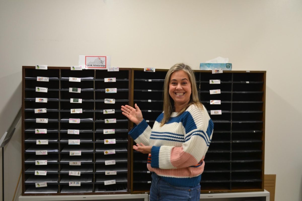 Jennifer Lowenbach stands in front of the wall of scholarships.