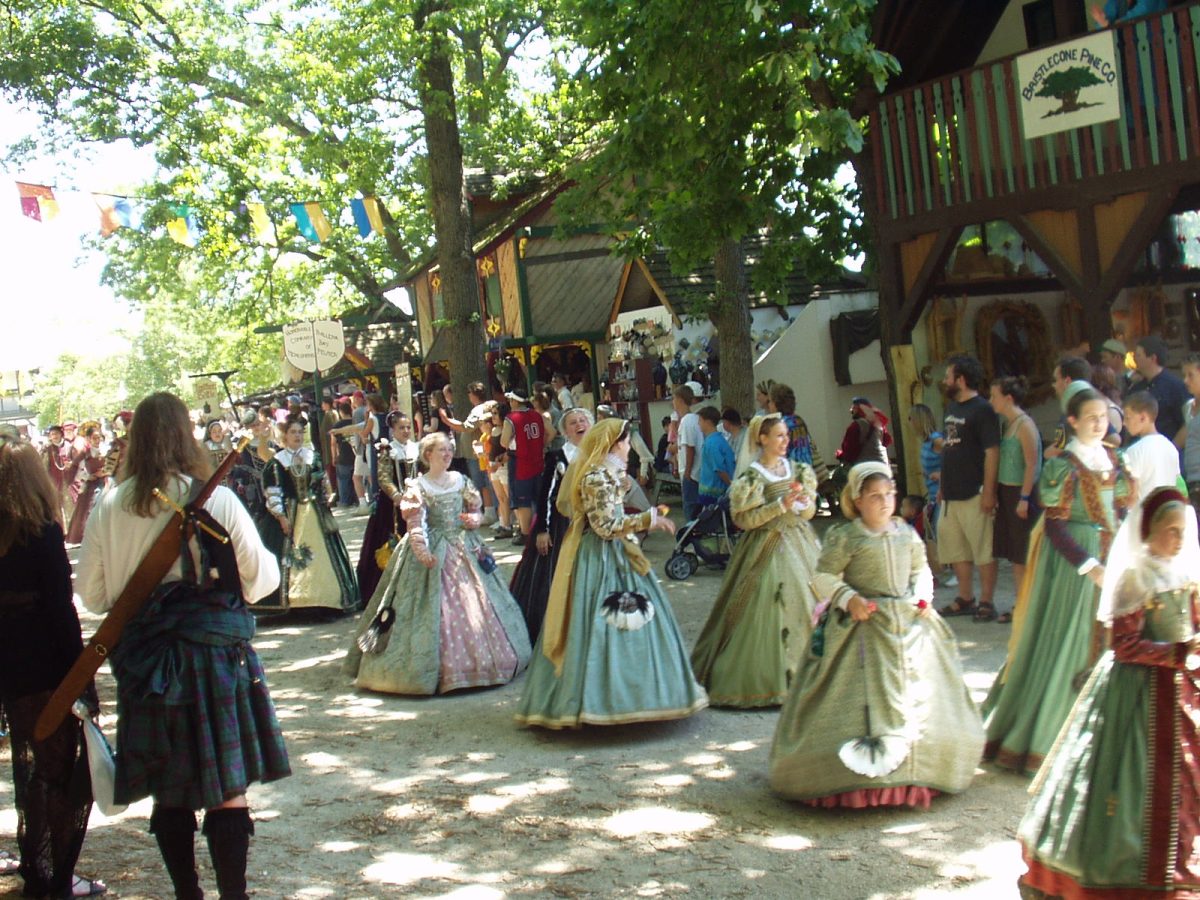 A Renaissance Festival taking place in the springtime where visitors are dressing up and enjoying performers. 