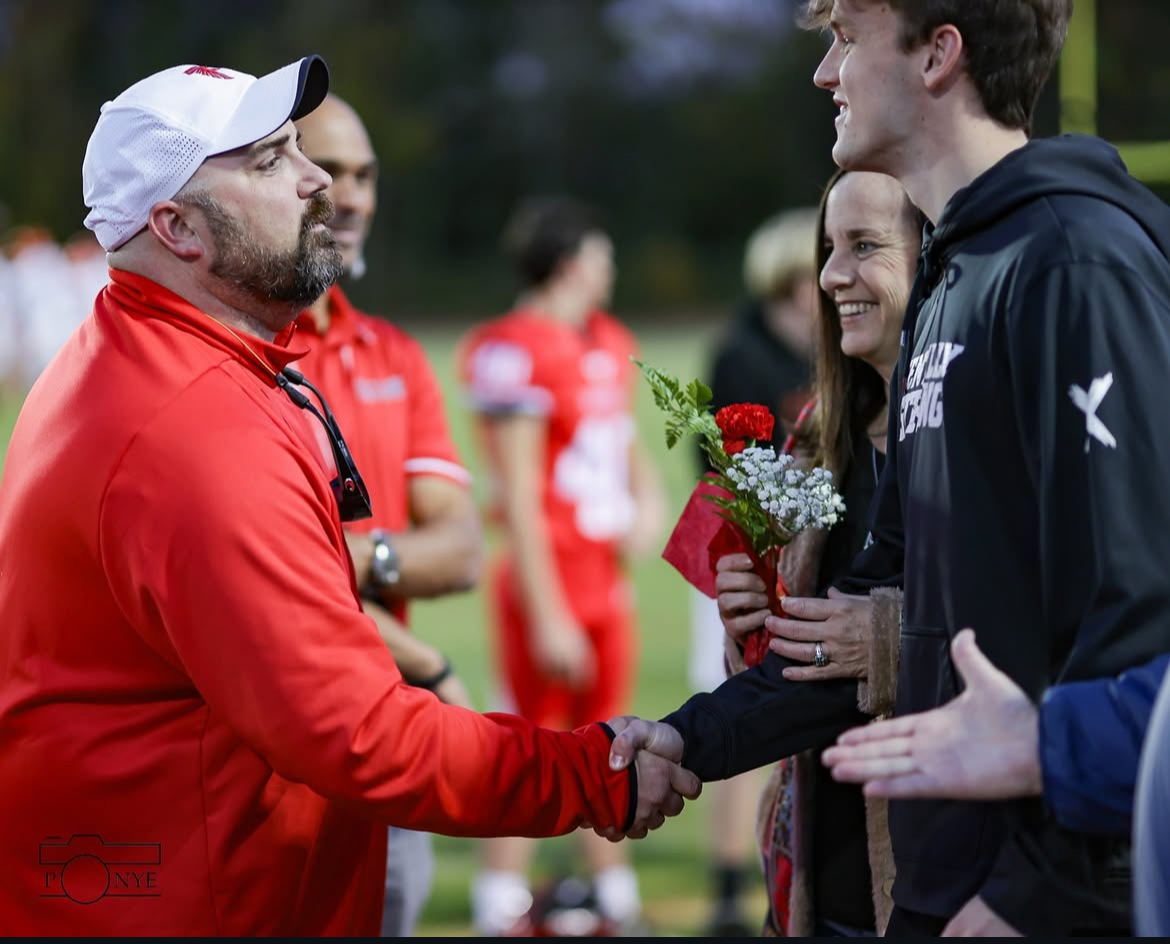 Dr. David Ferguson shakes hands with senior Dylan Donner and his mom on senior night.