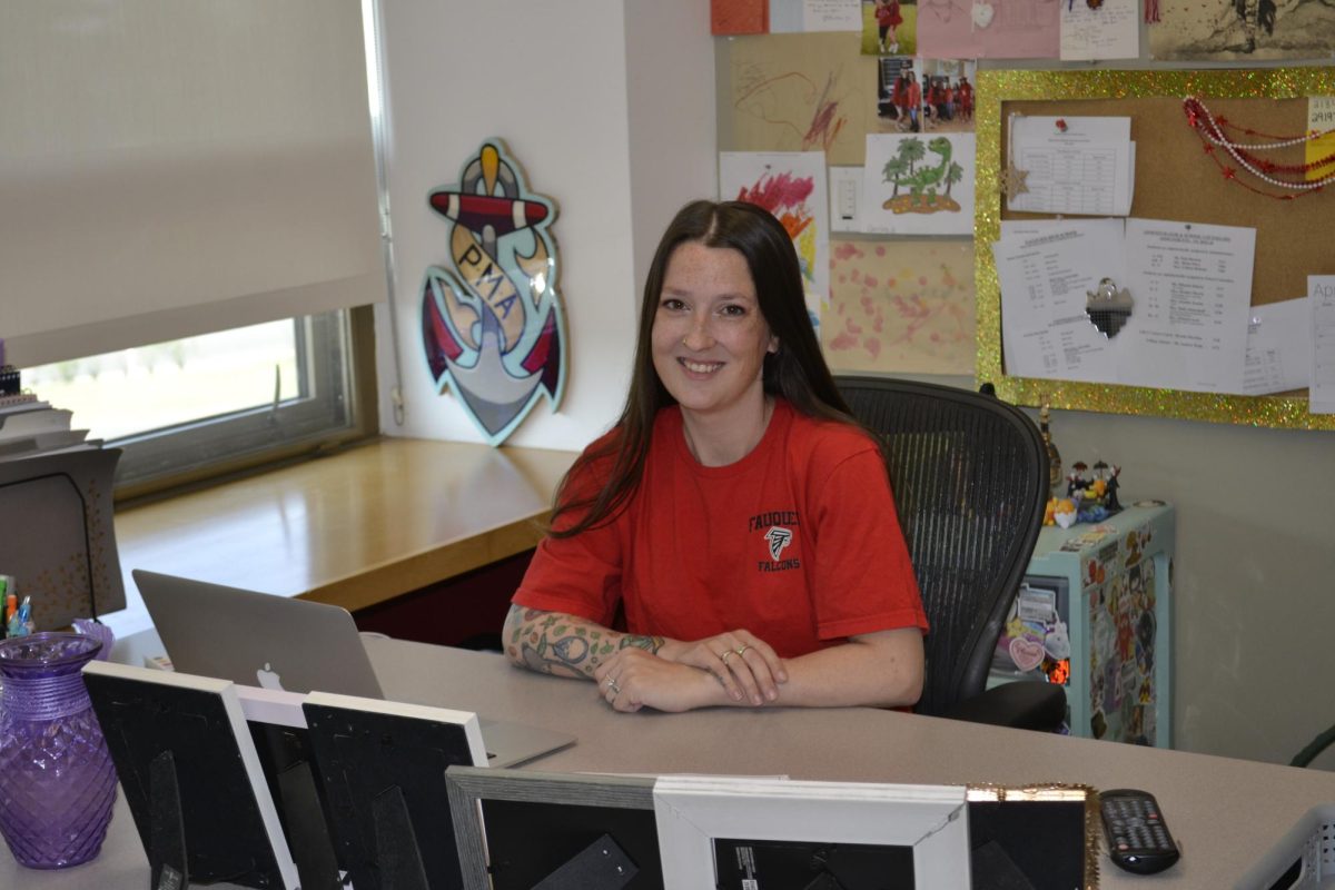Social Studies teacher Ansley Bogart sits smiling at her desk showing school spirit.